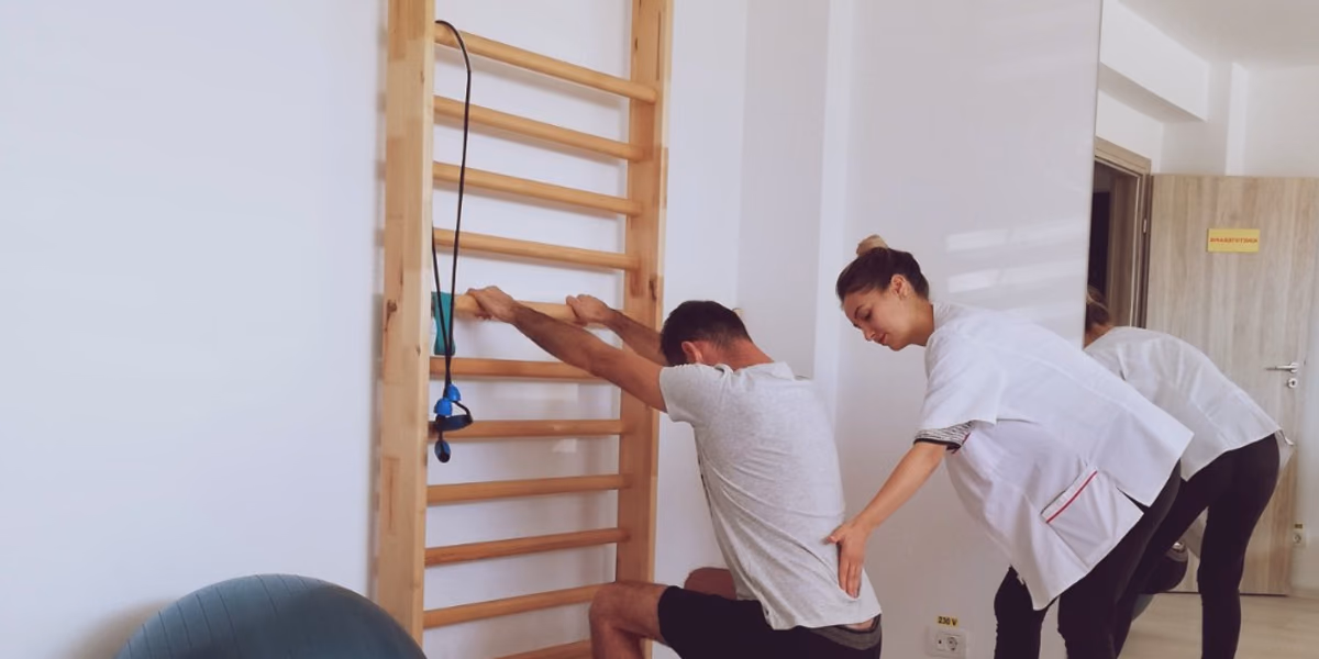 Kinetoterapeut ghidând un pacient la spalier, la Fiziokineto Clinic